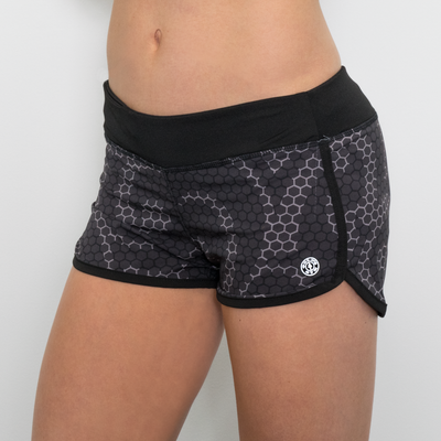 photo of model wearing advance ladies woven short in steel geo hex. waistband in black. golds gym weight plate logo in white. black overlapped seam on sides and around legs.