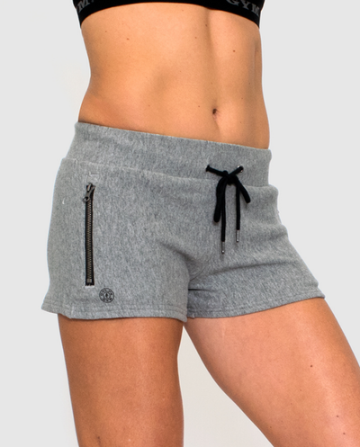 photo of model wearing advance french terry short in grey heather. black drawstring tie in waistband. small gold weight plate logo in black on right leg below zipper pocket.