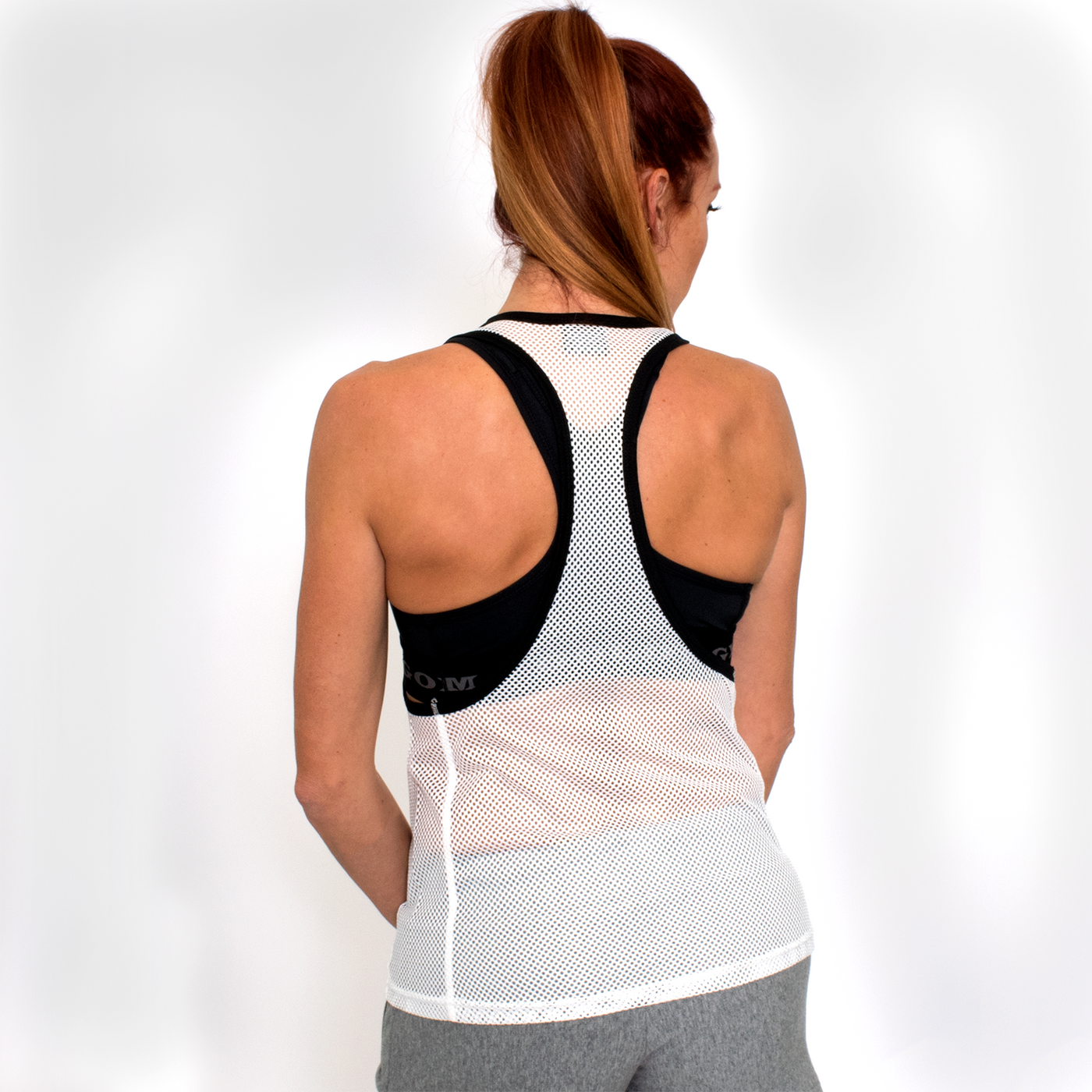 back view photo of model wearing advance mesh tease tank in white. black trim on neck and arm holes. 