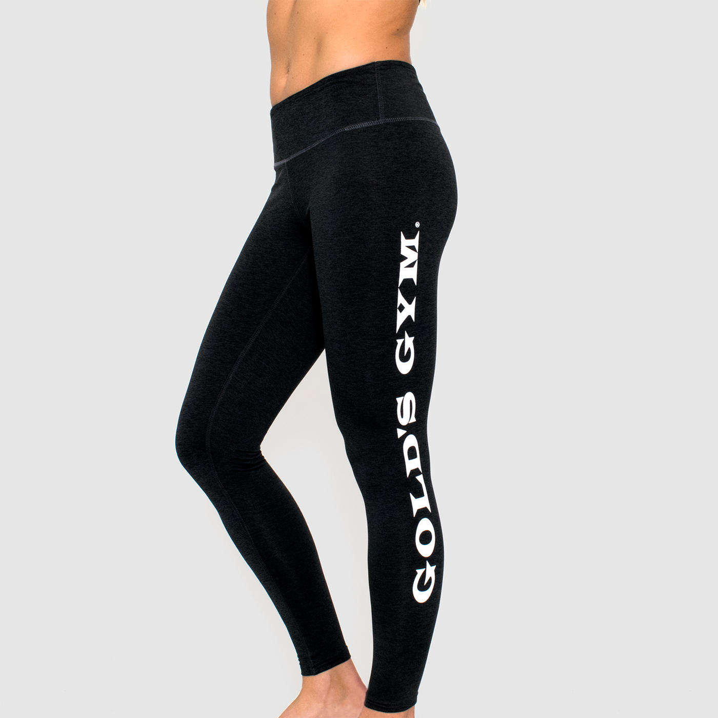 model of model wearing advance ladies legging in black heather. golds gym printed on left leg vertically in white.