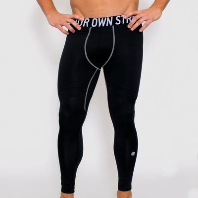 photo of model wearing advance mens compression tights in black. golds weight plate logo in white on left out calf. know your own strength printed on waistband. white seam visible on inner leg.