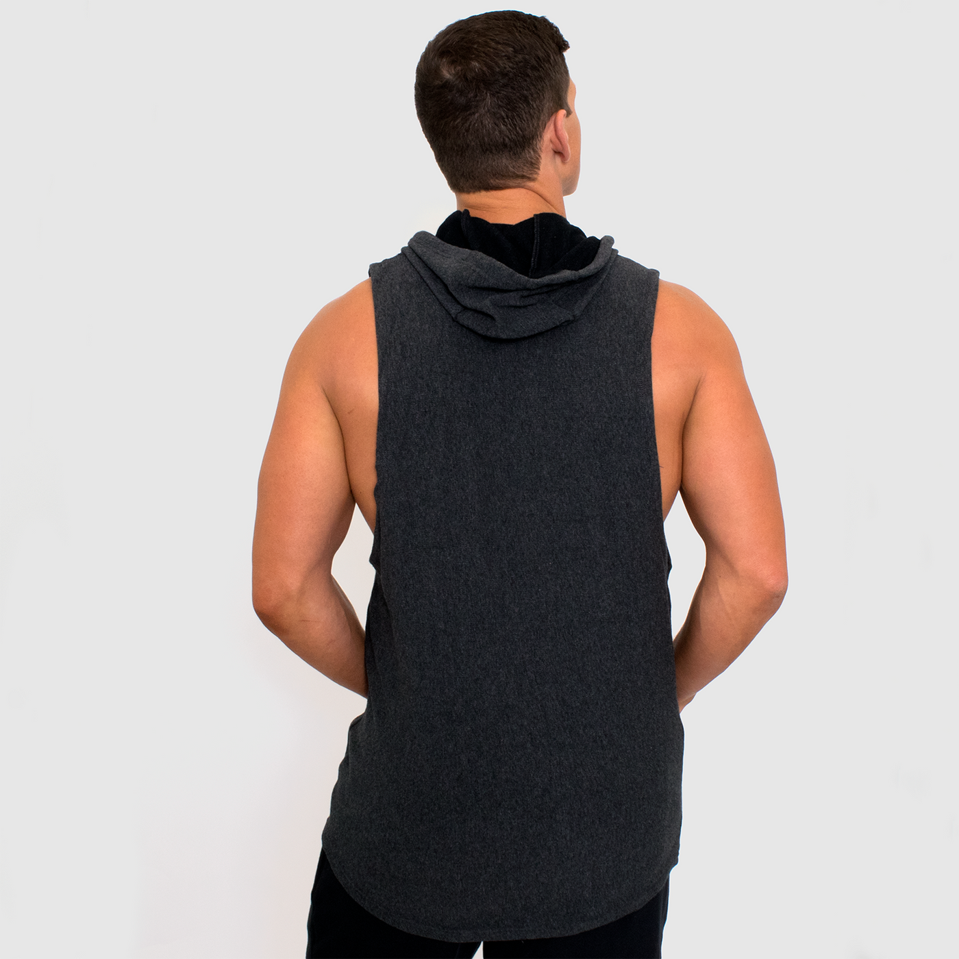 back view photo of model wearing advance mens sleeveless hoodie in black heather. hoodie shown down with black lining shown.