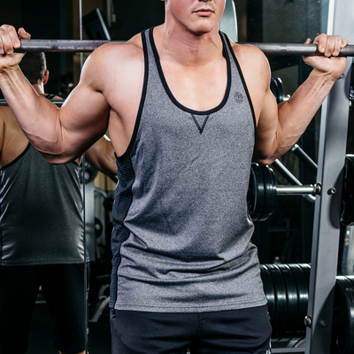 photo of model lifting barbell wearing advance performance stringer in athletic heather golds gym weight plate logo in black on upper left chest. black trim around arm and neck holes. black stripes on sides. stitched v under neck line. 