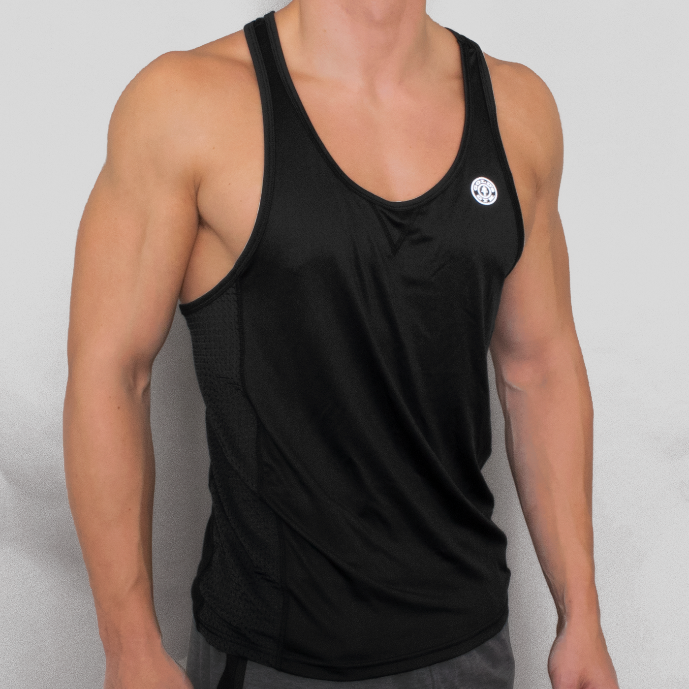 detail photo of model wearing advance performance stringer in black. golds gym weight plate logo in white on upper left chest. 